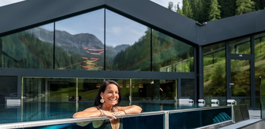 Eine Frau lehnt am Rand des Infinity-Pools und lacht.